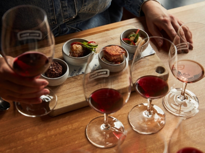 A woman sits down and holds a glass of Grenache with tasting plate